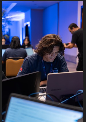 Léo Walker trabalhando em um computador durante uma competição de tecnologia